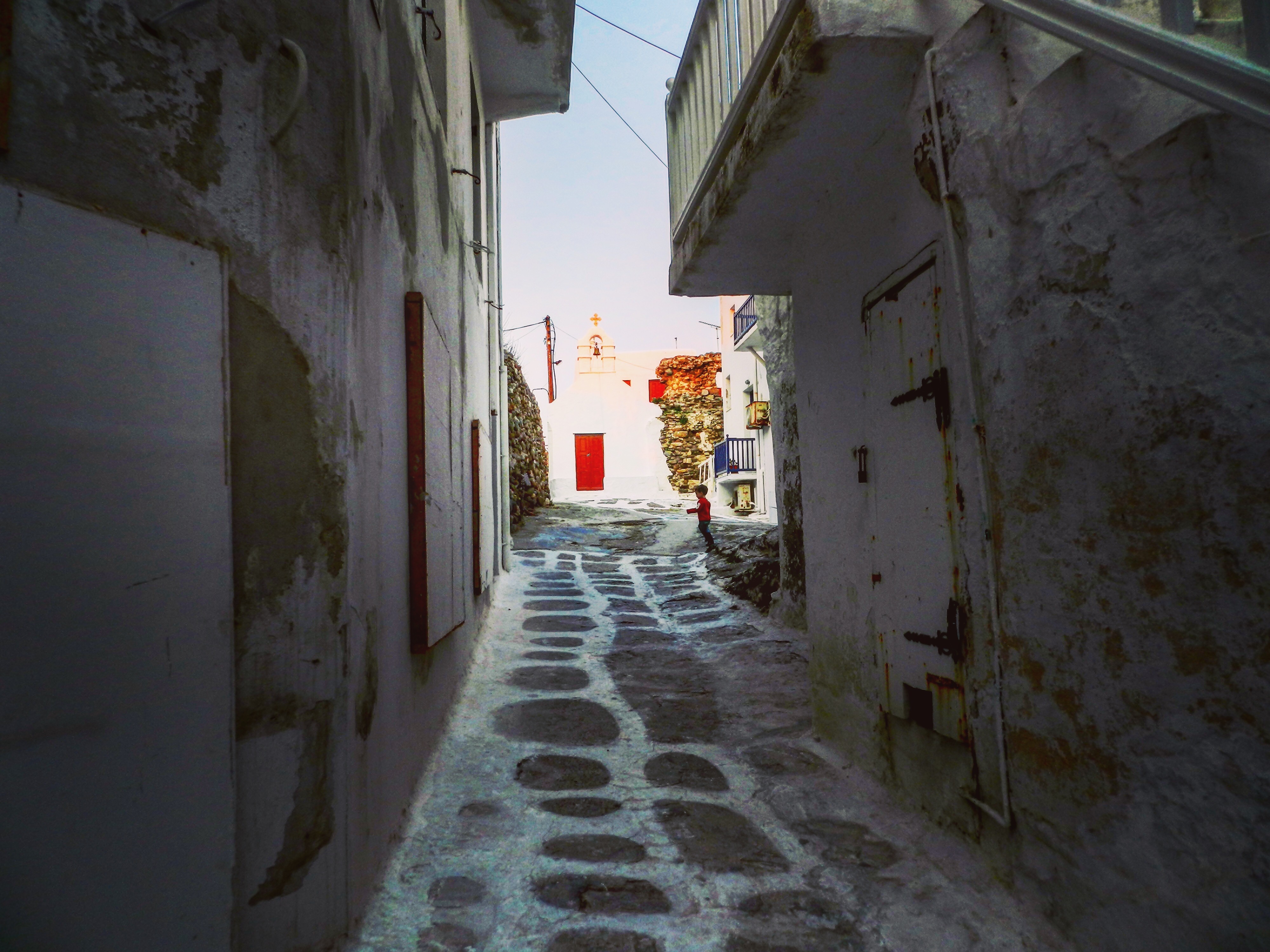 Narrow whitewashed alley in Mykonos with a chapel