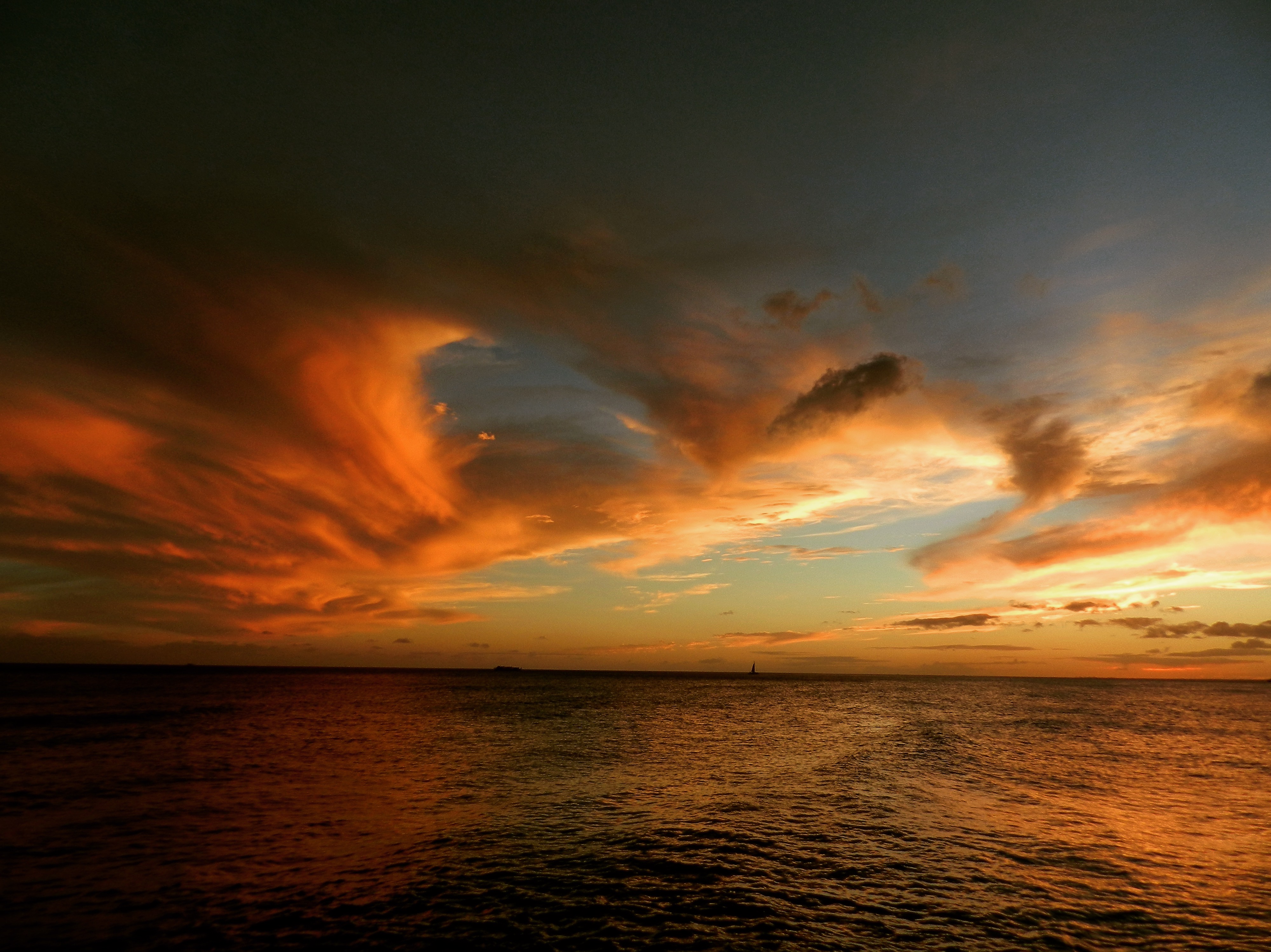 Ocean sunset with a distant sailboat